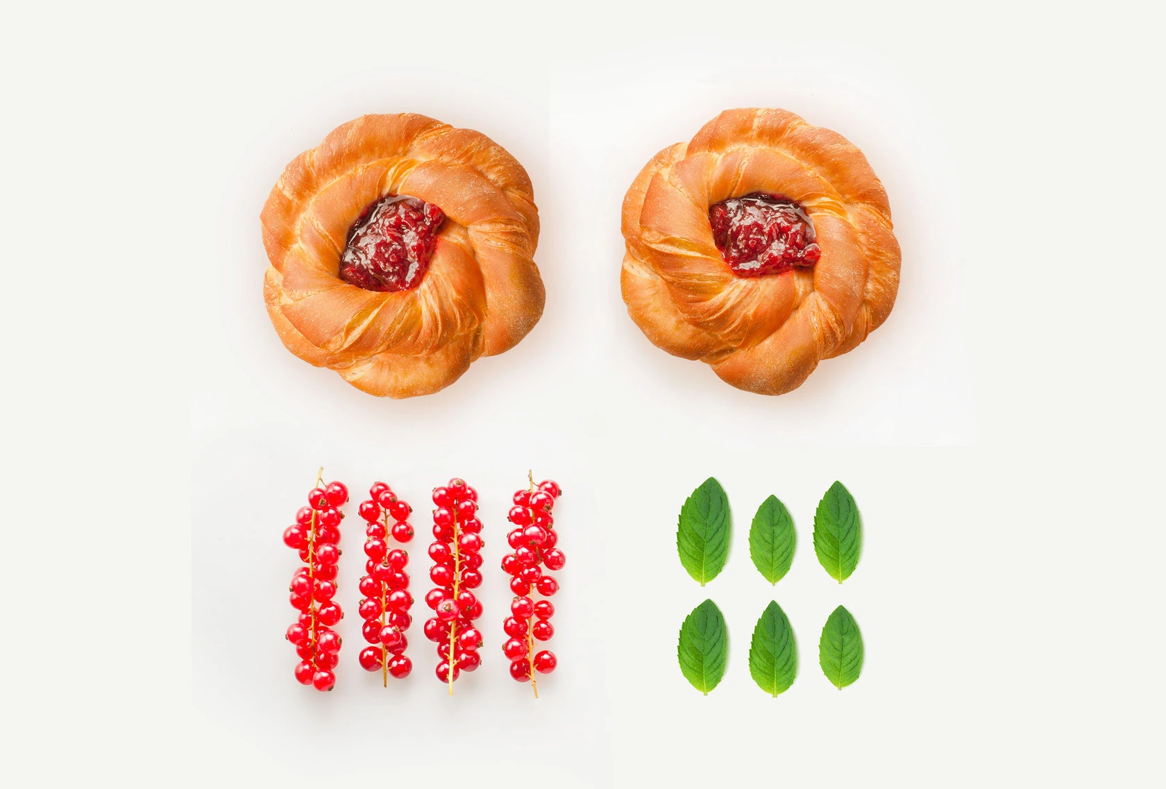Original studio product photograph of two filled buns, red berries and green leaves on a light background